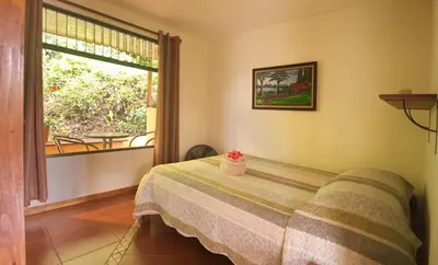 a bedroom with a bed and a window and a table at Casita Amapola in Tilarán