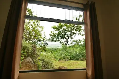 a window in a room with a view of a field at Casita Amapola in Tilarán