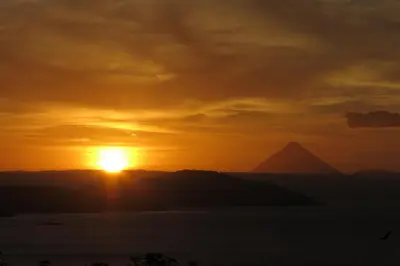a sunset over the water with a mountain in the background at Casita Amapola in Tilarán