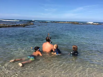 a man and two children in the water at the beach at Aloha Surf Nosara - Kahala Hui Cabins #2 in Nosara