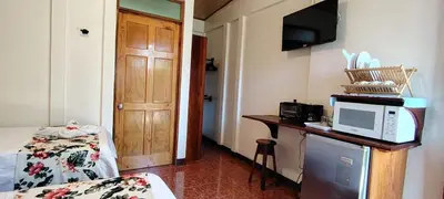a room with a bed and a desk with a microwave at Aloha Surf Nosara - Kahala Hui Cabins #2 in Nosara