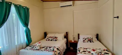 two beds in a small room with green curtains at Aloha Surf Nosara - Kahala Hui Cabins #2 in Nosara