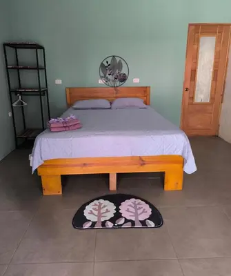 a bedroom with a bed with a wooden bed frame at Almendros de Osa Lodge in Uvita