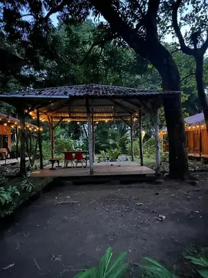 a wooden pavilion with a bench under a tree at Almendros de Osa Lodge in Uvita