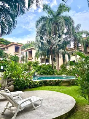 a resort with a pool and two chairs and palm trees at Birds of a Feather 2BR2BA Ocotal Coastal Retreat in Ocotal