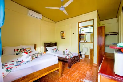 a bedroom with two beds and a bathroom at Aloha Surf Nosara - Kahala Hui Cabins #3 in Nosara