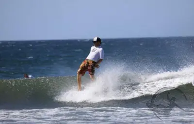 a man riding a wave on a surfboard in the ocean at Aloha Surf Nosara - Kahala Hui Cabins #3 in Nosara