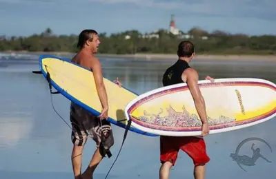 two men walking on the beach with their surfboards at Aloha Surf Nosara - Kahala Hui Cabins #3 in Nosara