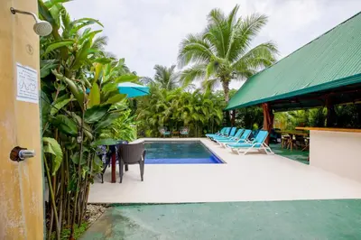 a pool at a resort with chairs and a table at Aloha Surf Nosara - Kahala Hui Cabins #4 in Nosara