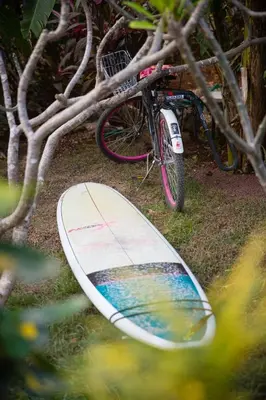 a surfboard laying on the ground next to a bike at Aloha Surf Nosara - Kahala Hui Cabins #4 in Nosara