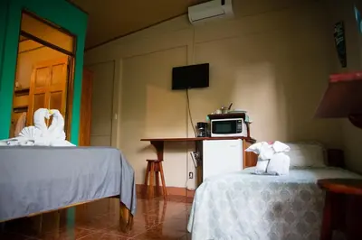a room with two beds and a table with a microwave at Aloha Surf Nosara - Kahala Hui Cabins #4 in Nosara