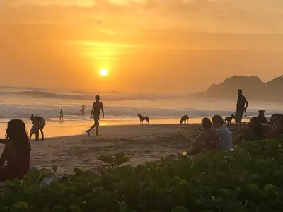 a group of people on the beach at sunset at Aloha Surf Nosara - Kahala Hui Cabins #4 in Nosara