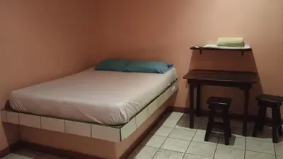 a small bedroom with a bed and a desk at Hotel MANAA in Cariari