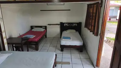 a room with two beds and a table and a chair at Hotel MANAA in Cariari