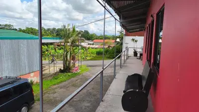 a red building with a car parked outside of it at Hotel MANAA in Cariari