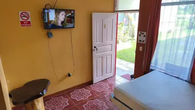 a room with a tv on the wall and a door at Hotel MANAA in Cariari