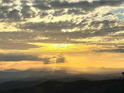 a sunset in the mountains with clouds in the sky at Wood cozy cabin with ocean views in Boston