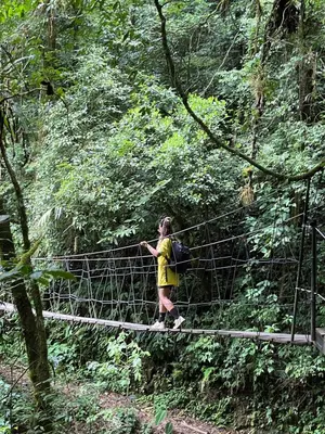 a woman walking across a suspension bridge in the forest at Wood cozy cabin with ocean views in Boston