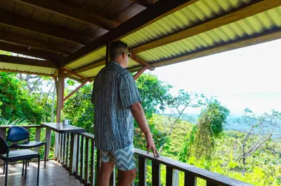 a man standing on a porch looking out at the forest at Wood cozy cabin with ocean views in Boston