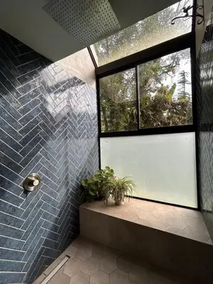 a shower with blue tiles and a window at Los Guayabos in Sarchí
