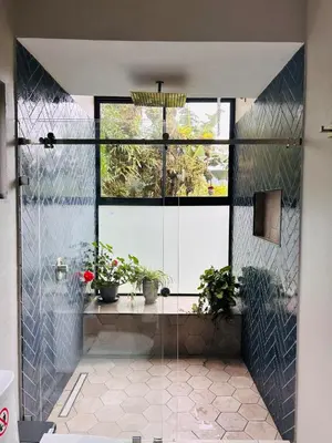 a bathroom with a glass door with potted plants at Los Guayabos in Sarchí