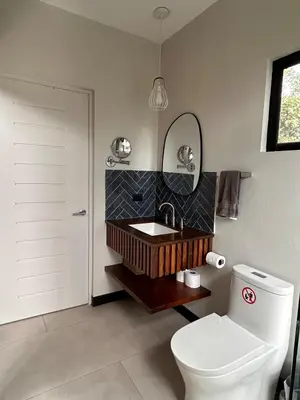 a bathroom with a toilet and a sink and a mirror at Los Guayabos in Sarchí