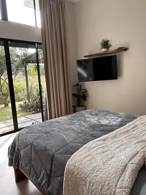 a bedroom with a bed and a flat screen tv at Los Guayabos in Sarchí