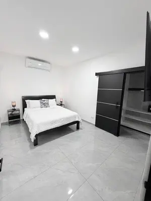 a white bedroom with a bed and a television at Casa Azul Jaco in Jacó
