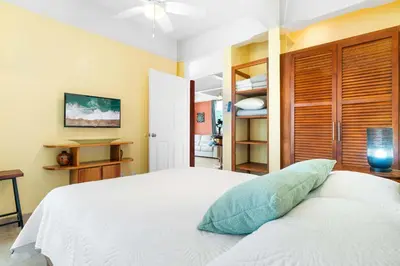 a bedroom with a white bed with a blue pillow on it at Modern Top-Floor Condo with Panoramic Views and Community Pool in Coco