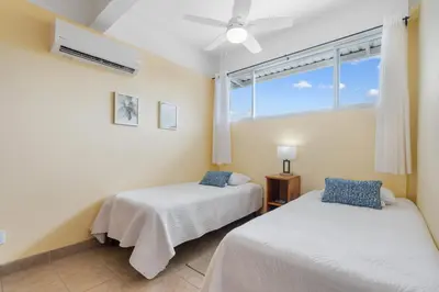 two beds in a room with a window at Modern Top-Floor Condo with Panoramic Views and Community Pool in Coco