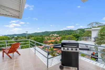 an outdoor balcony with a stove and a chair at Modern Top-Floor Condo with Panoramic Views and Community Pool in Coco