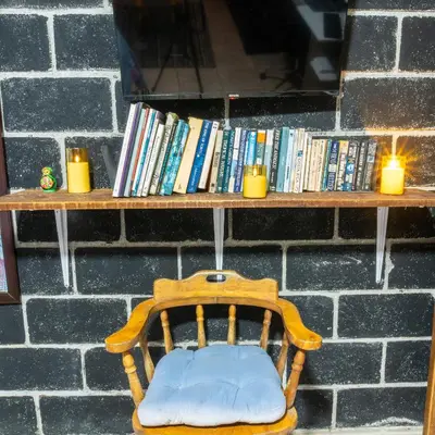 a wooden chair sitting in front of a shelf with books at 31 Studio Apartment in Heredia