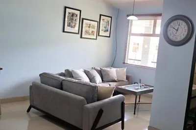 a living room with a couch and a clock on the wall at Southern Escapes Apartment in Quepos