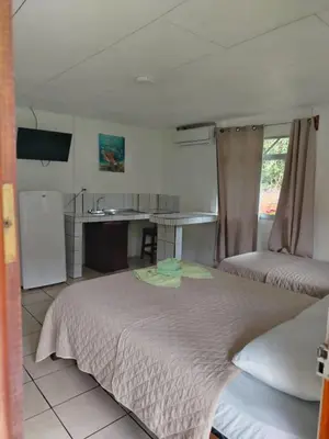 a bedroom with a large bed and a kitchen at Cabinas Hidalgo in Ojochal