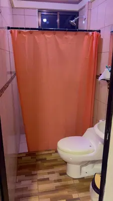 a bathroom with an orange shower curtain and a toilet at La Casa del Tucán in Puerto Limón