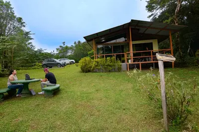 two people sitting at a picnic table in front of a building at Las Marias Monteverde - Mountain View Cottages & Gardens in Monteverde Costa Rica
