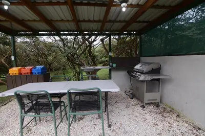 a table and chairs and a grill in a backyard at Las Marias Monteverde - Mountain View Cottages & Gardens in Monteverde Costa Rica