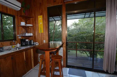 a kitchen with a counter and a table with two stools at Las Marias Monteverde - Mountain View Cottages & Gardens in Monteverde Costa Rica