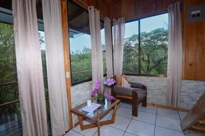 a living room with a couch and a table with flowers at Las Marias Monteverde - Mountain View Cottages & Gardens in Monteverde Costa Rica