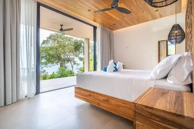 a bedroom with a large bed and a large window at Casa LaVista - by Pura Villas in Uvita
