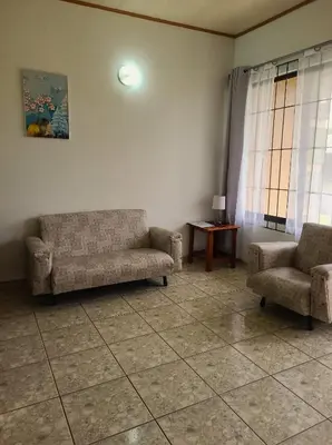 a living room with two chairs and a couch and a table at Arenal Dreams Apartments in Fortuna
