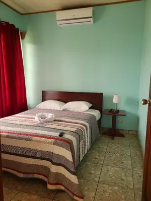 a bedroom with a bed with a blanket and a fan at Arenal Dreams Apartments in Fortuna