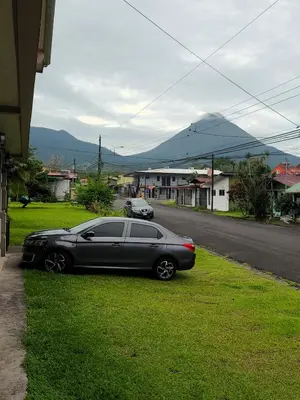 a black car parked on the grass next to a street at Arenal Dreams Apartments in Fortuna