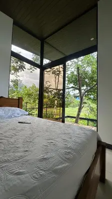 a bedroom with a bed and a large window at Tree of Heaven Lodge in San Isidro