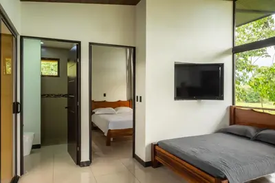 a bedroom with a bed and a flat screen tv at Tree of Heaven Lodge in San Isidro