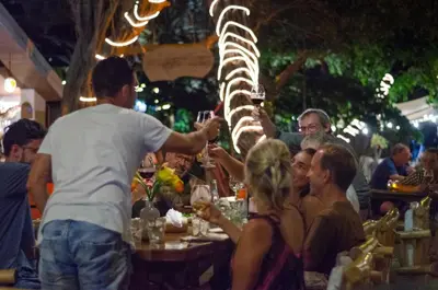 a group of people sitting at a table with a dinosaur skeleton at LA DOLCE VITA - on the Beach - Samara in Sámara