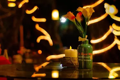 a candle and a vase with flowers on a table at LA DOLCE VITA - on the Beach - Samara in Sámara
