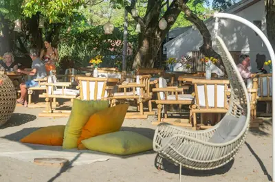 a white rattan chair with colorful pillows on the ground at LA DOLCE VITA - on the Beach - Samara in Sámara