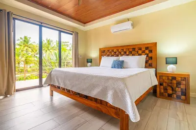 a bedroom with a bed and a large window at Sleep 11-Beachfront-Pool-Wildlife-100MB -Suites in Parrita