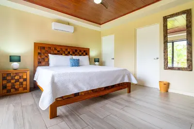 a bedroom with a large bed with a wooden headboard at Sleep 11-Beachfront-Pool-Wildlife-100MB -Suites in Parrita